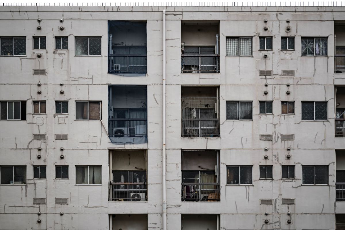灯りのついた住戸と空室が混在する老朽アパートの外観。事故物件の一棟アパートは空室連鎖が査定額を左右する