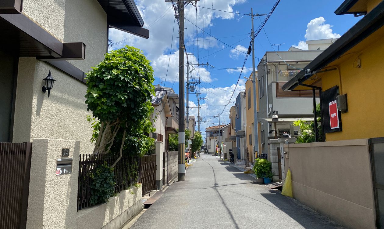 大阪市内の住宅街。木造戸建が並ぶ細い道路と青空