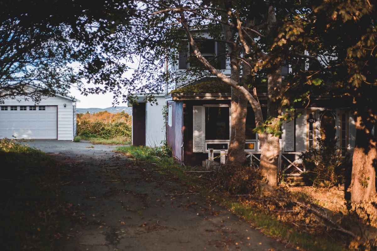 草木が伸び、誰も住まなくなった空き家の外観。相続放棄をしても建物はそのまま残り続ける